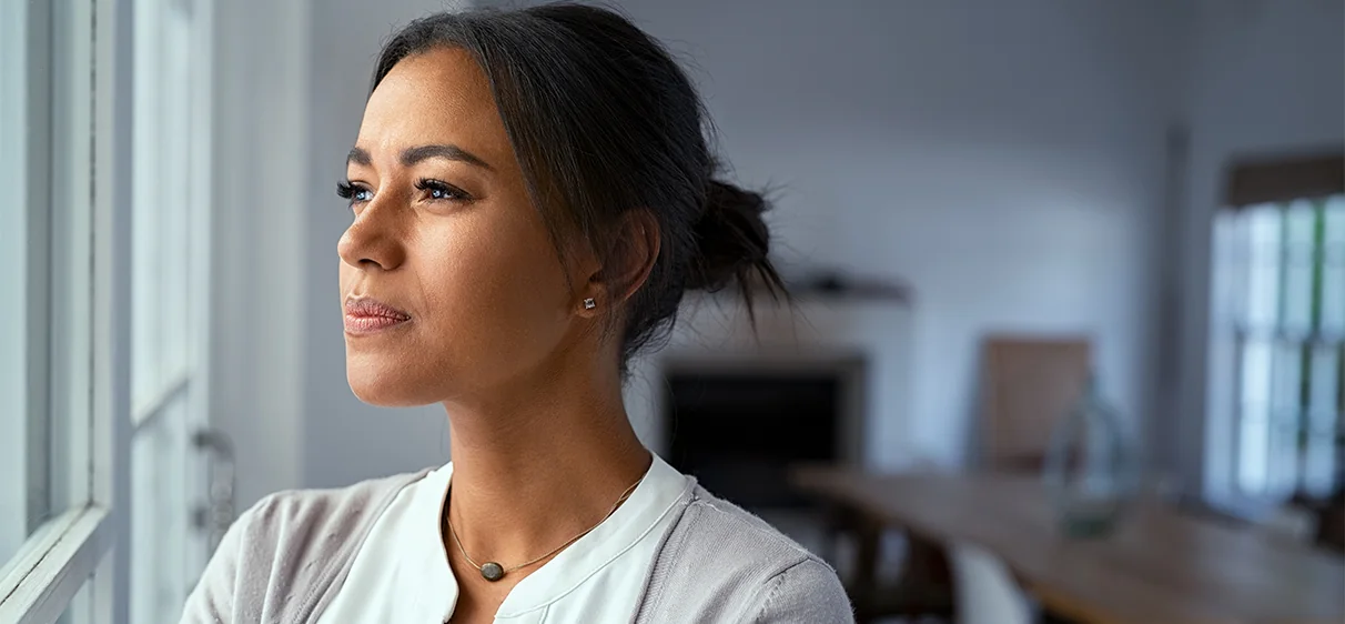 Woman looking out window in uncertainty