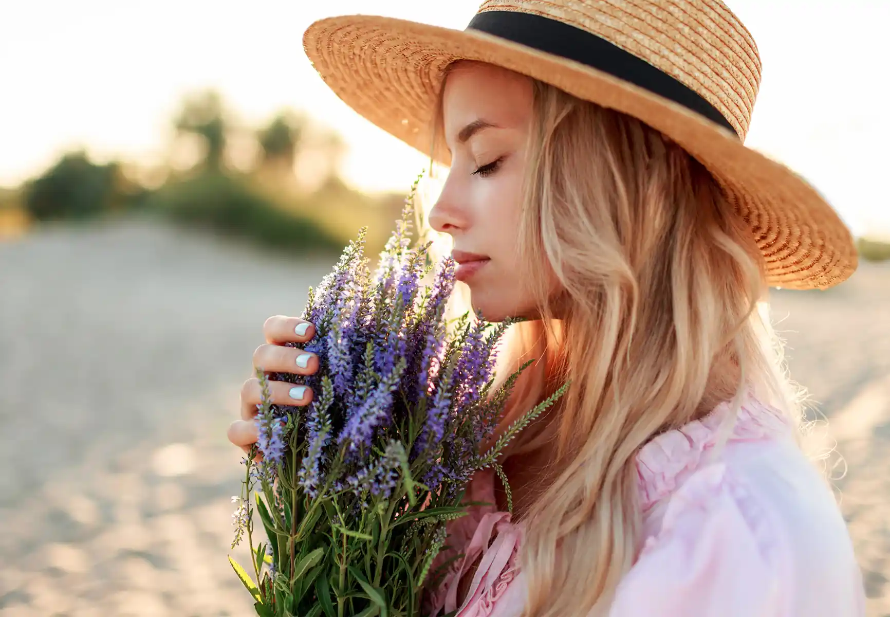 Woman smelling bouquet of flowers at the beach