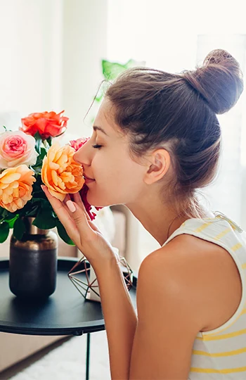 Woman smelling fresh roses in vase