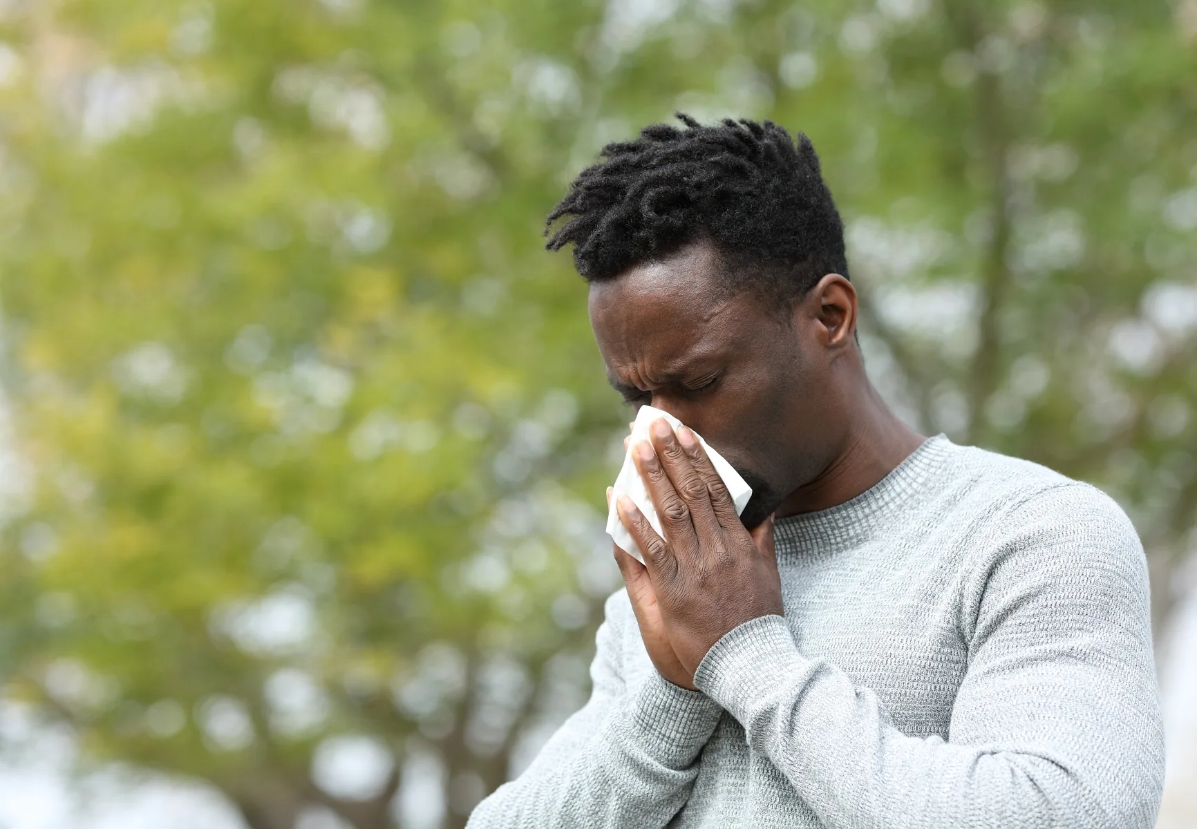 African American man blowing his nose outside