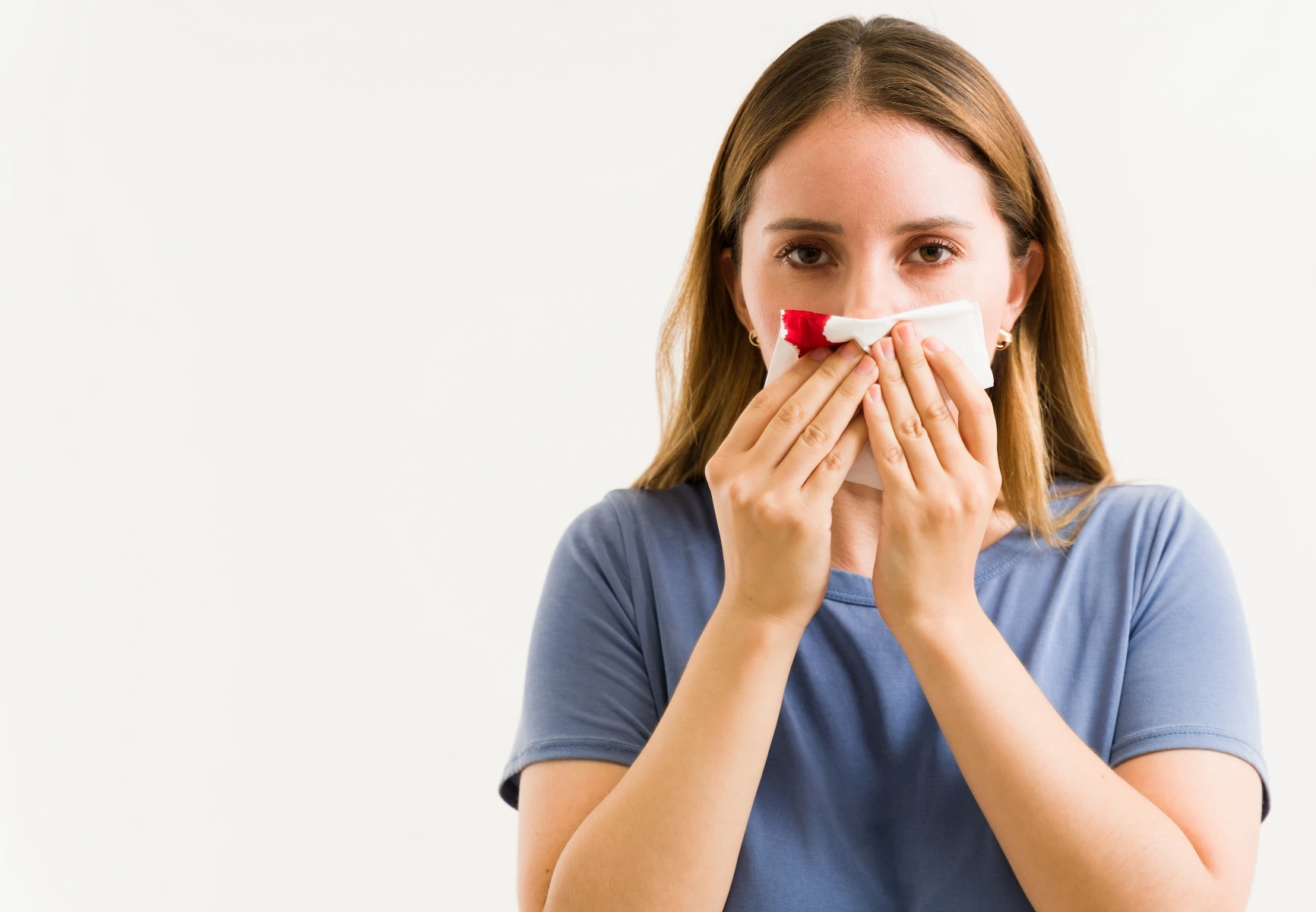 Woman stopping her nosebleed with a tissue